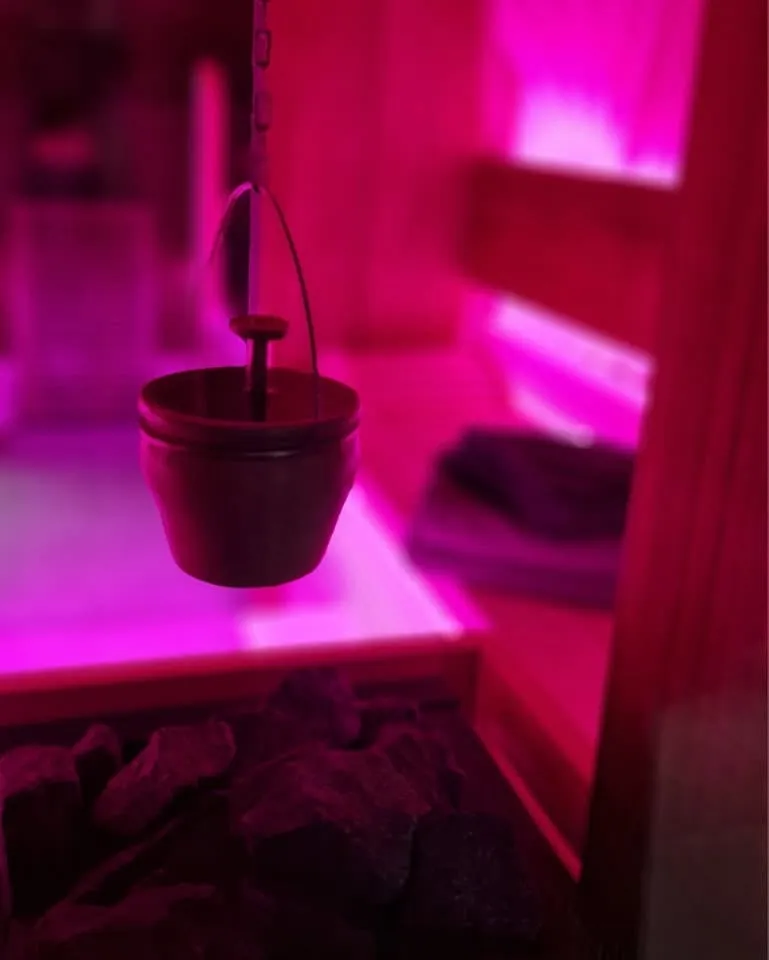 De saunaemmer in het gekleurde licht van de sauna